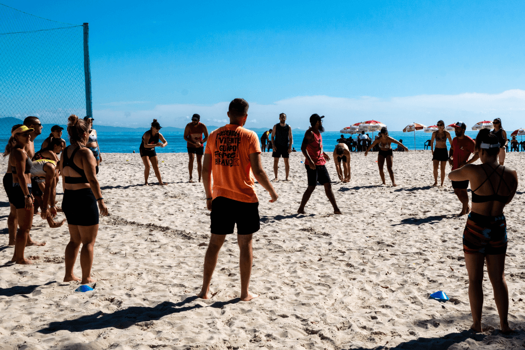 Treino do CrossFit em Canasvieiras, Florianópolis — aquecimento em círculo na praia com coach orientando