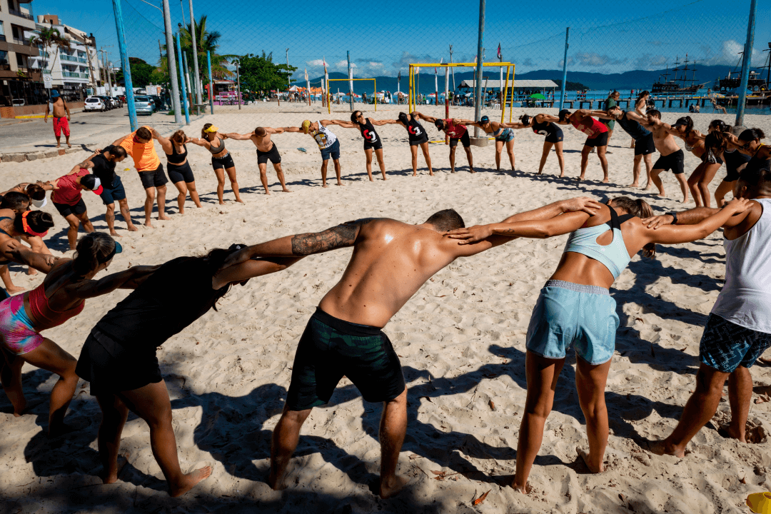 Turma do CrossFit Canasvieiras realizando alongamento em círculo na areia de Canasvieiras