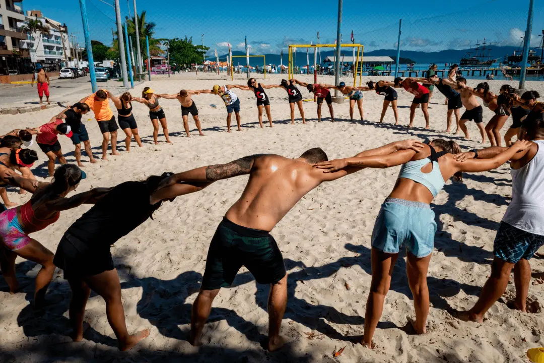 Turma do CrossFit Canasvieiras realizando alongamento em círculo na areia de Canasvieiras