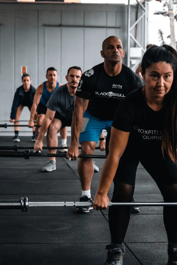 Alunos alinhados executando técnica de levantamento terra (deadlift) dentro do box