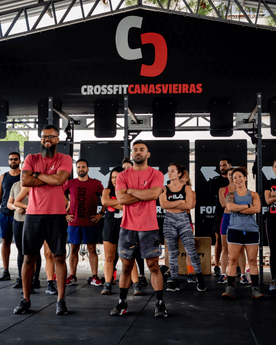 Coaches do CrossFit Canasvieiras a frente e os alunos atrás com logo do no banner acima