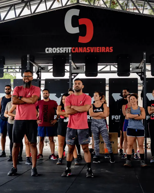 Coaches do CrossFit Canasvieiras a frente e os alunos atrás com logo do no banner acima